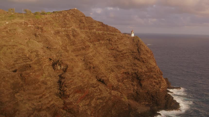 An aerial view of a lighthouse on a cliff on the shore