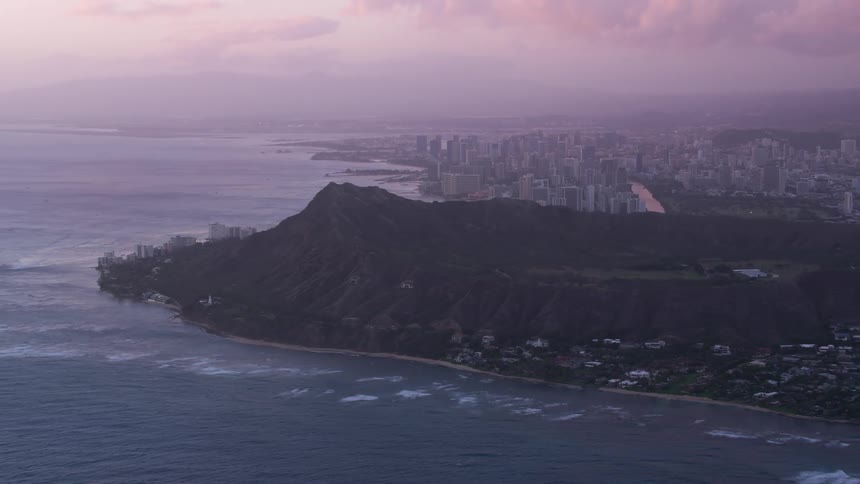 A volcano crater is on the coast near a large city