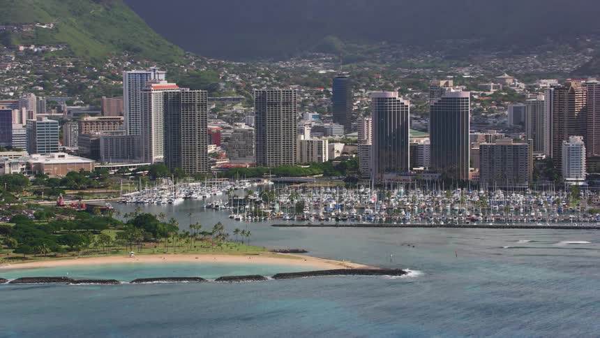 Aerial view of a boats on a marina in front of the skyline of a coastal city