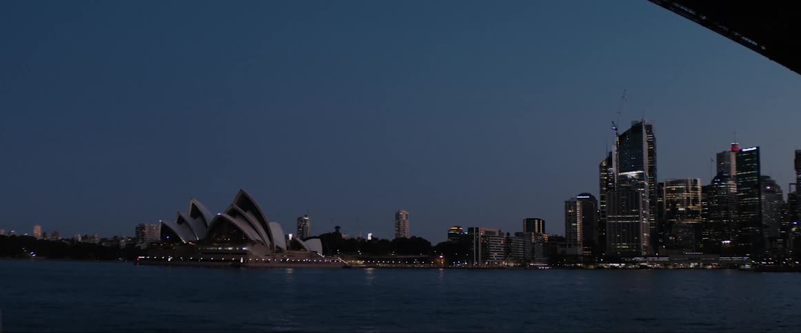 A coastal city skyline with buildings and trees with the sky and clouds in the background