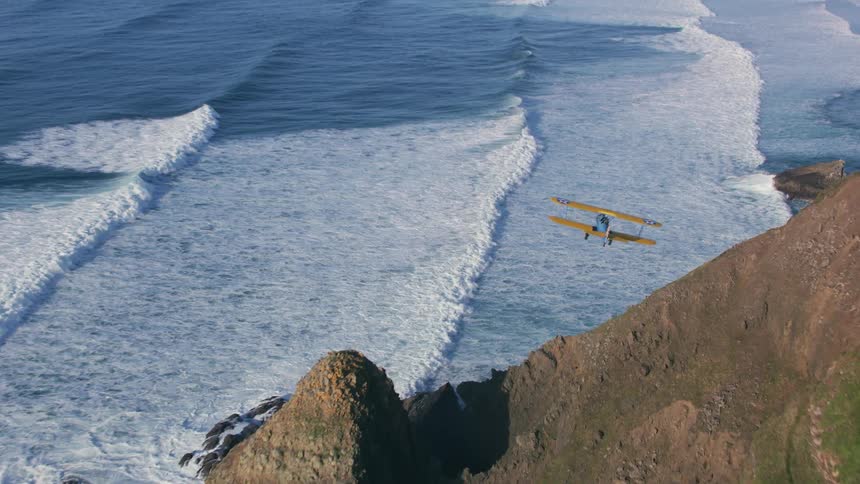 A biplane flying along the coast