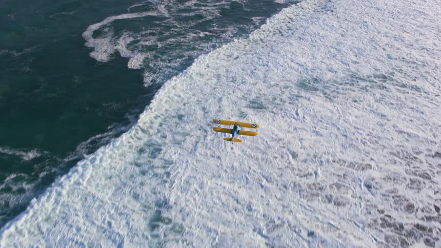A biplane flying over an ocean