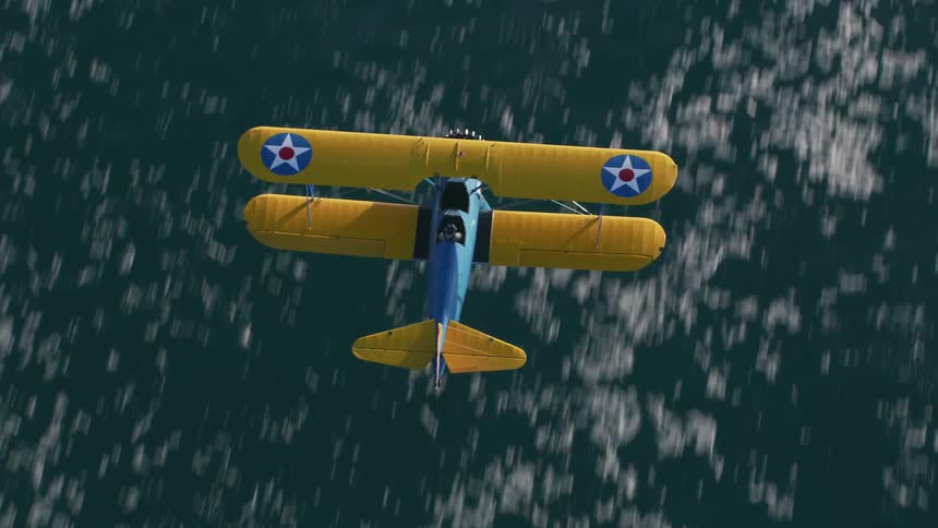Aerial shot of a biplane flying over water