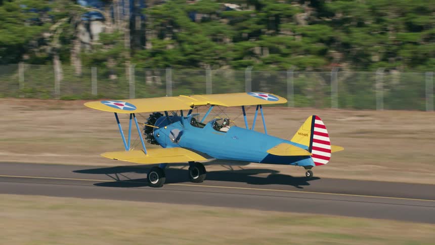A small airplane goes down a runway and then takes off in to the air