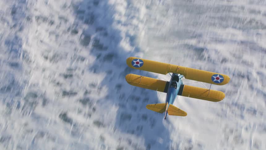 A biplane flies over snow covered ground
