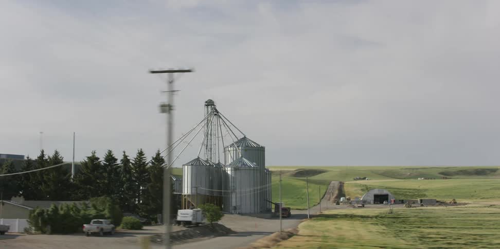Steel grain silos connected by pipes on farm land
