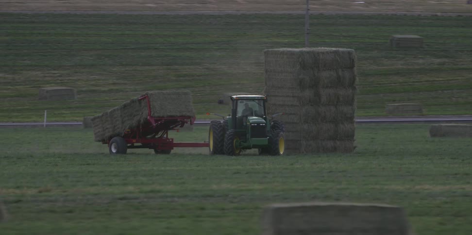 A tractor is stacking hay on the farm