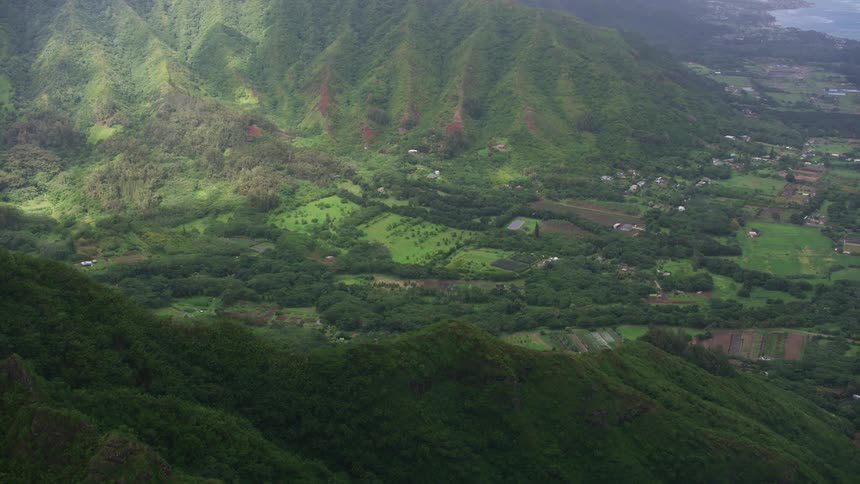 An aerial view of a rural countryside with rolling hills and water in the distance