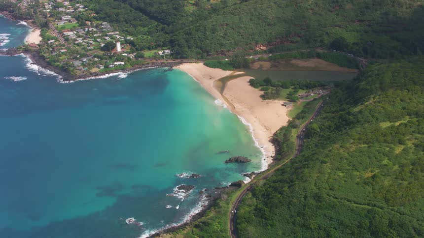 An aerial view of a coastal area shows an inviting beach and some buildings nearby