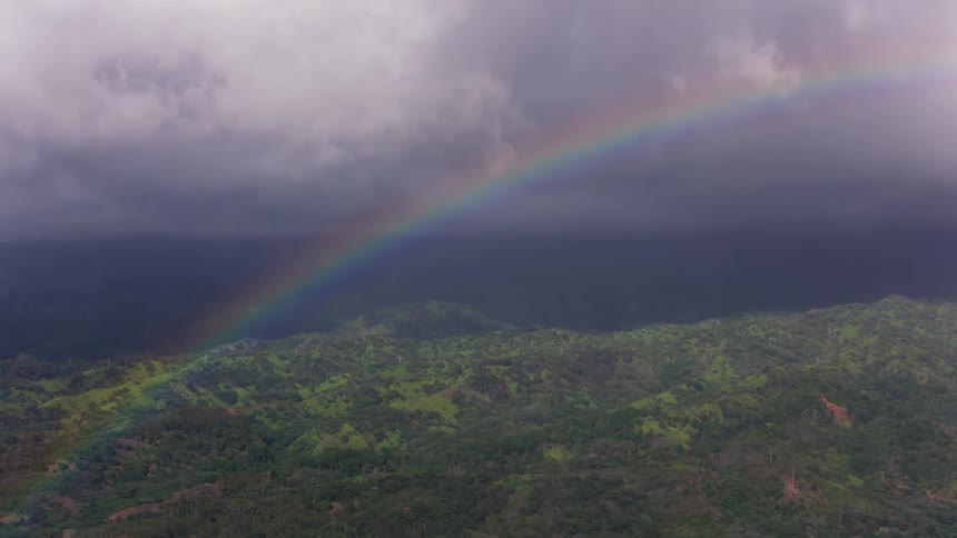 A rainbow stretches across a cloud filled sky