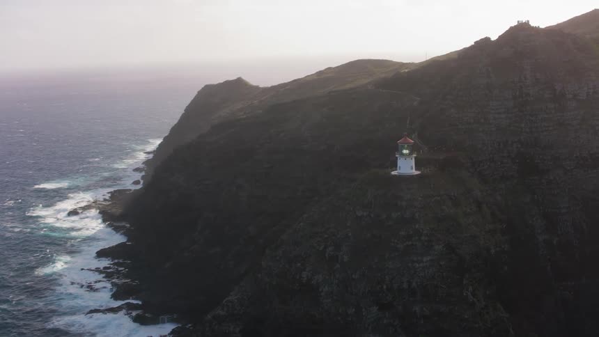 A lighthouse by a cliff with the ocean sky and clouds in the background