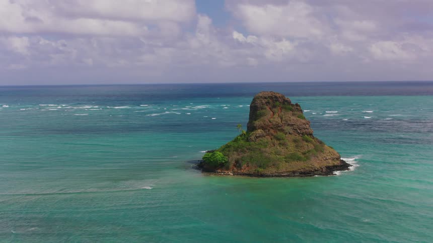 An aerial view of a tall rock in the ocean