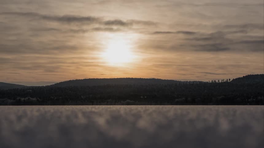The sun rises over a forested hill