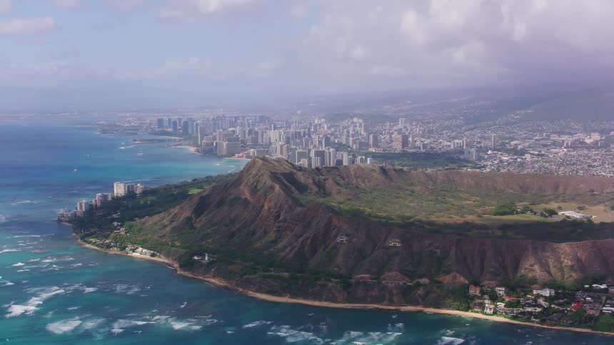 A coastal city skyline with buildings and trees with the sky and clouds in the background