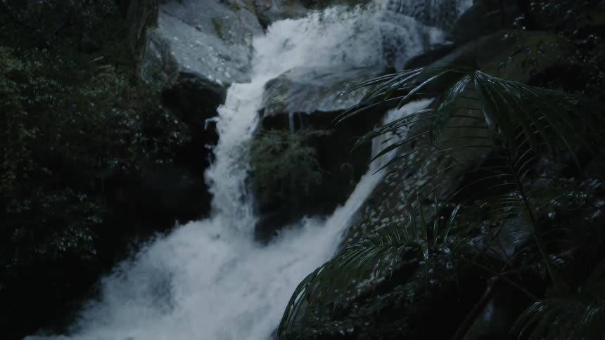 A waterfall crashes over rocks in to a river below