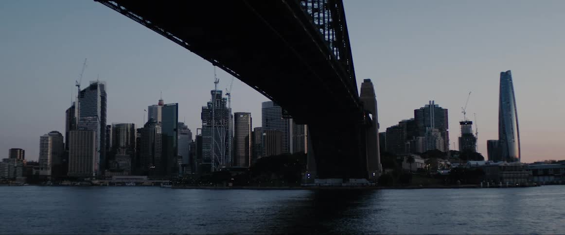 A bridge over a river with buildings the sky and clouds in the background