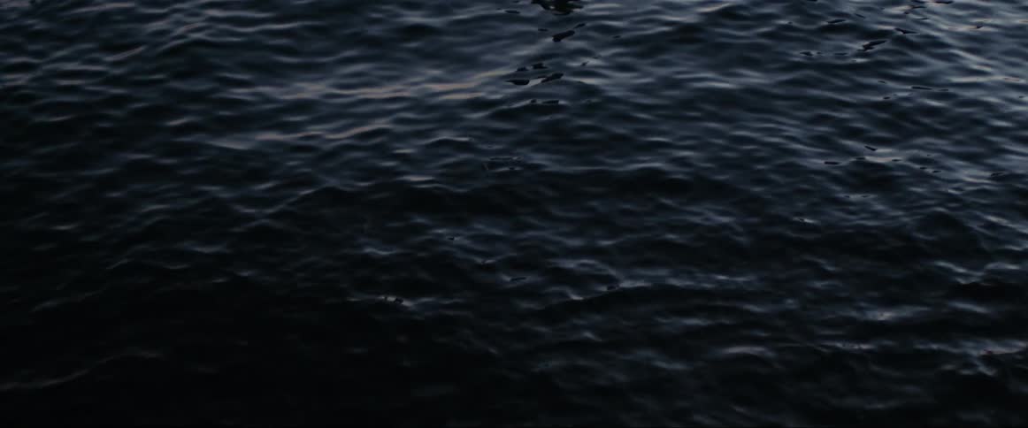 Dark areas and highlights show over surface of dark rippling water