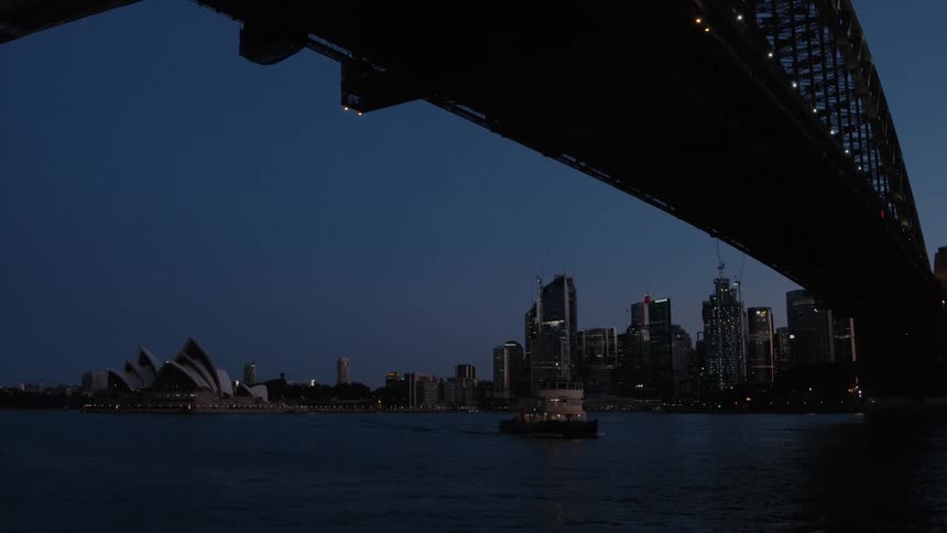 Ferry driving under the sydney harbour bridge near the opera house