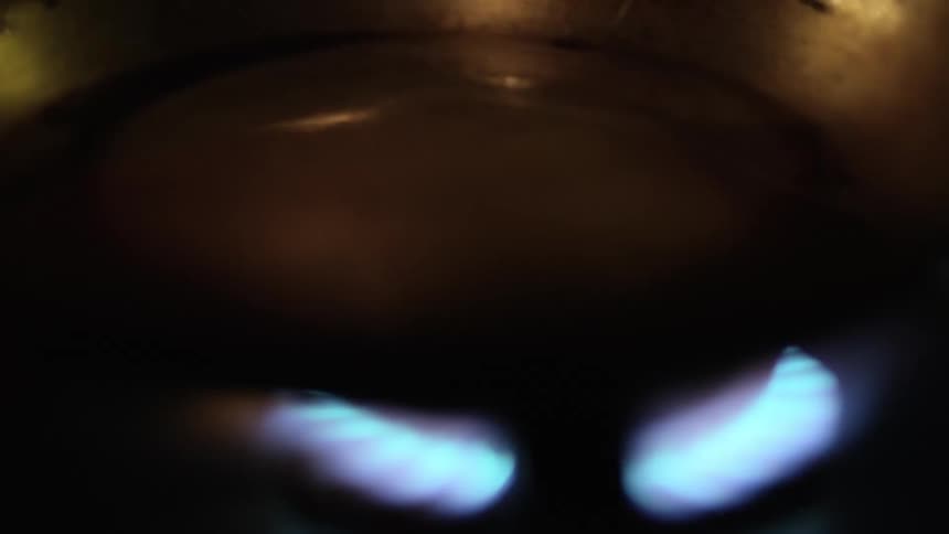 A skillet is set on an open blue flame