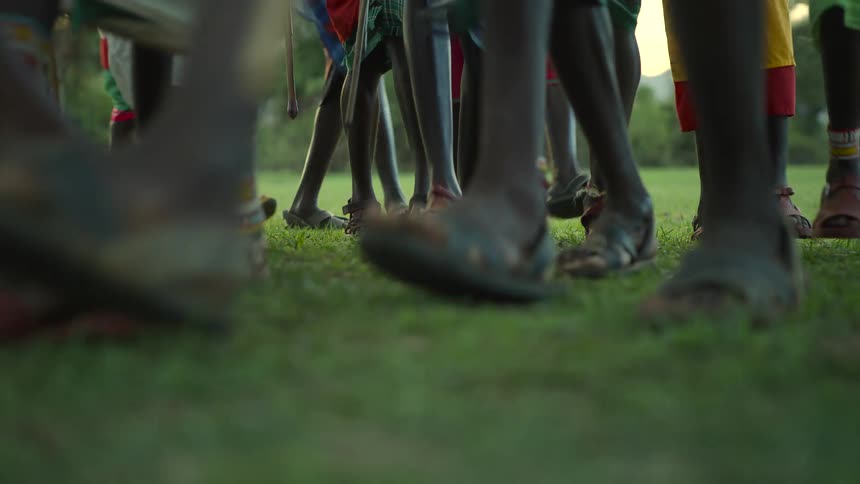 People in traditional dress are dancing on the grass