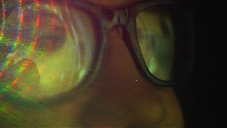 A person is watching something that is reflecting on their glasses