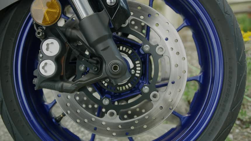 A motorcycle wheel is next to some grass