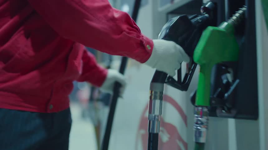 A person putting gas into a car at night