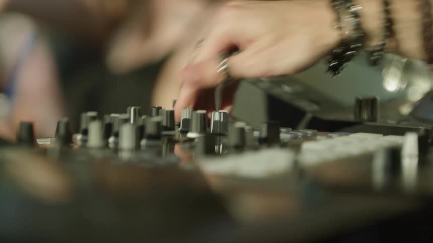 Women dancing with a person with rings turning knobs on a mixer