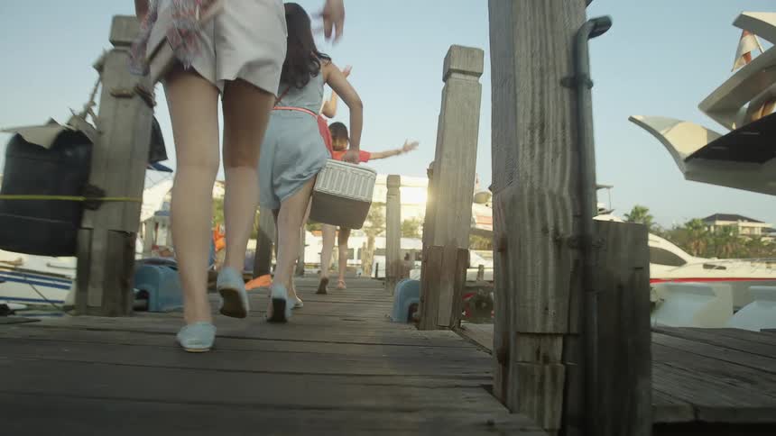 Three females walk across a pier towards boats in the marina