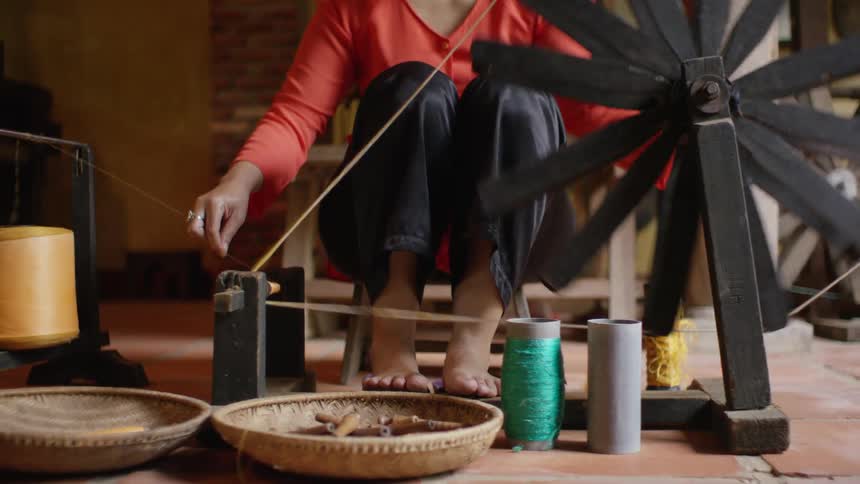 A person sits and holds a piece of thread going through multiple spins