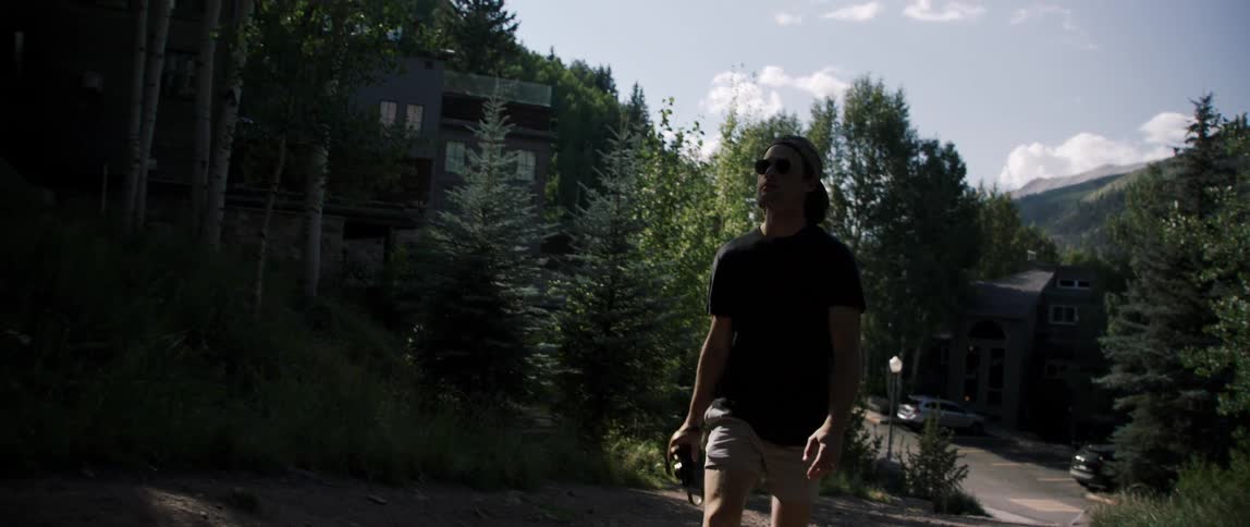 A man walks up a steep dirt road in a mountain community