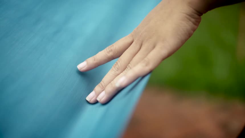 A person runs their hand along some blue fabric