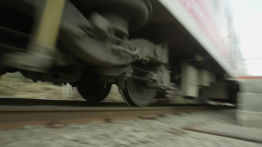 A train travels along a railway through a poor neighborhood during the day