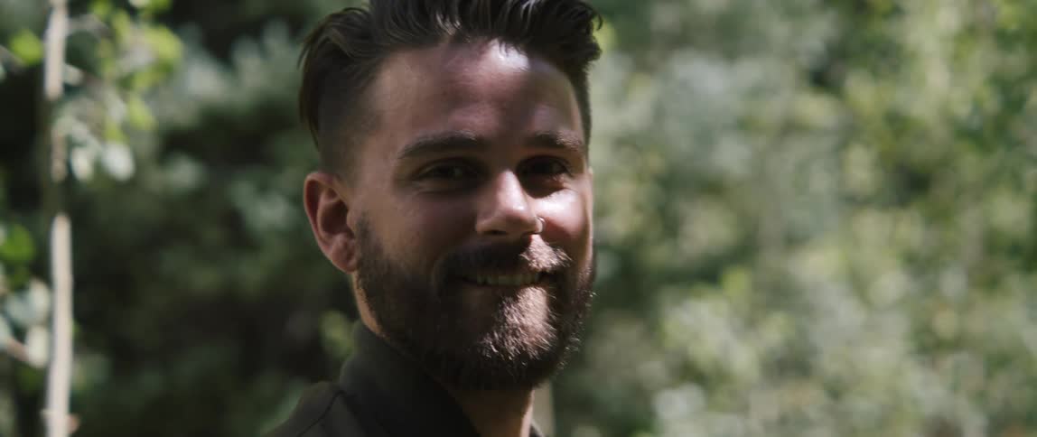 A man smiles outside on a sunny day
