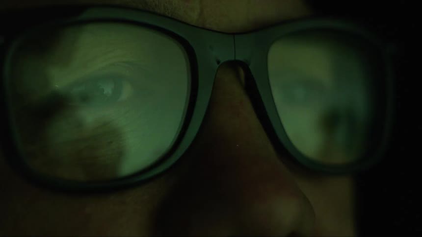 The display is reflecting on the mans glasses