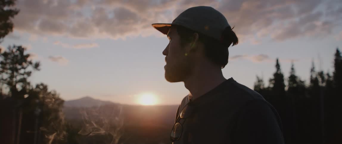 A man smoking in front of a sunset