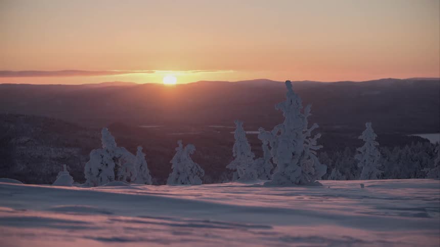 Time lapse of winter sun setting beyond hills covered with snow