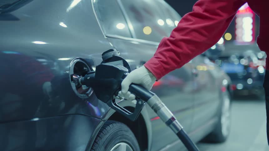 A person wears gloves as they pump gas for two seconds before putting the nozzle back