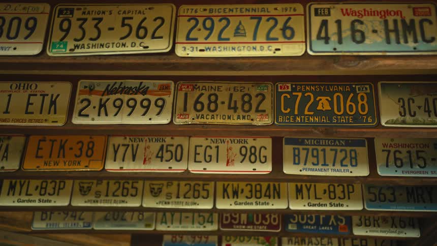 A collection of license plates from different states displayed on wooden ceiling beams