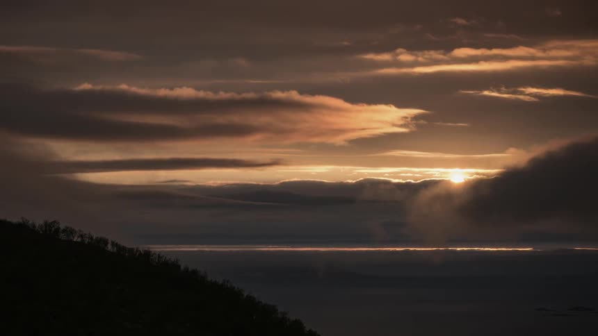 Orange clouds form and pass at sunset in timelapse
