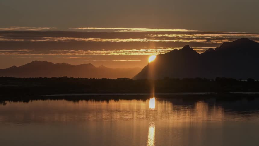 The midnight sun disappears behind mountains