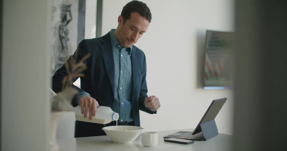 A man pours milk into a bowl then picks it up to eat