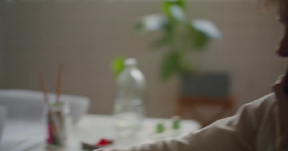 Young man talking on the phone while working on a laptop at home