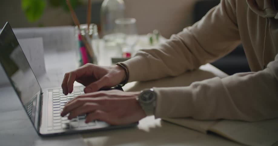 A man sits at a desk and types on a laptop
