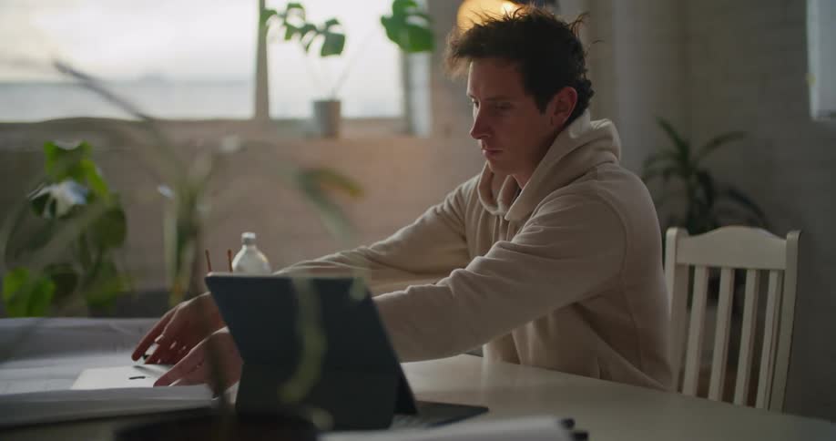 Man working from home sitting at a desk opens a laptop