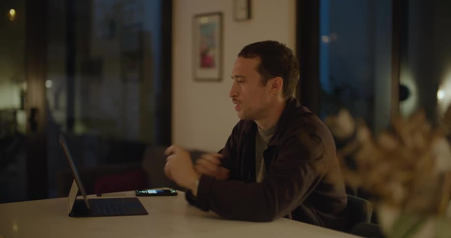 A man uses his laptop for a video call while sitting at his kitchen island