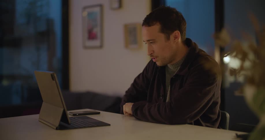 A man points and gestures as he talks on a video call on a tablet