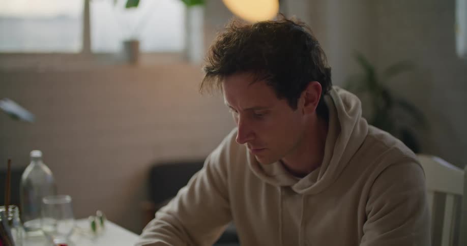 A man sits at a table and writes in a book