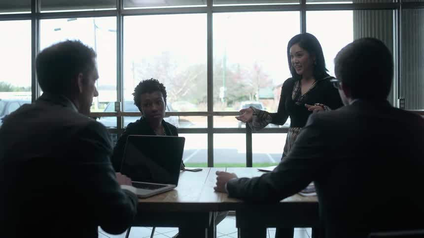 A woman is giving a presentation to people at a table