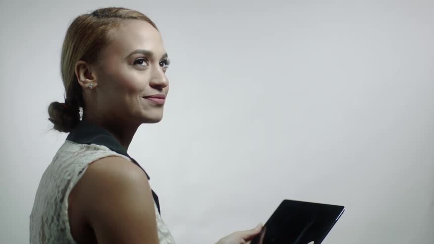 A woman using a tablet smiles and looks up